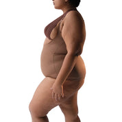 Curvy model showcasing a stylish brown bodysuit in profile.