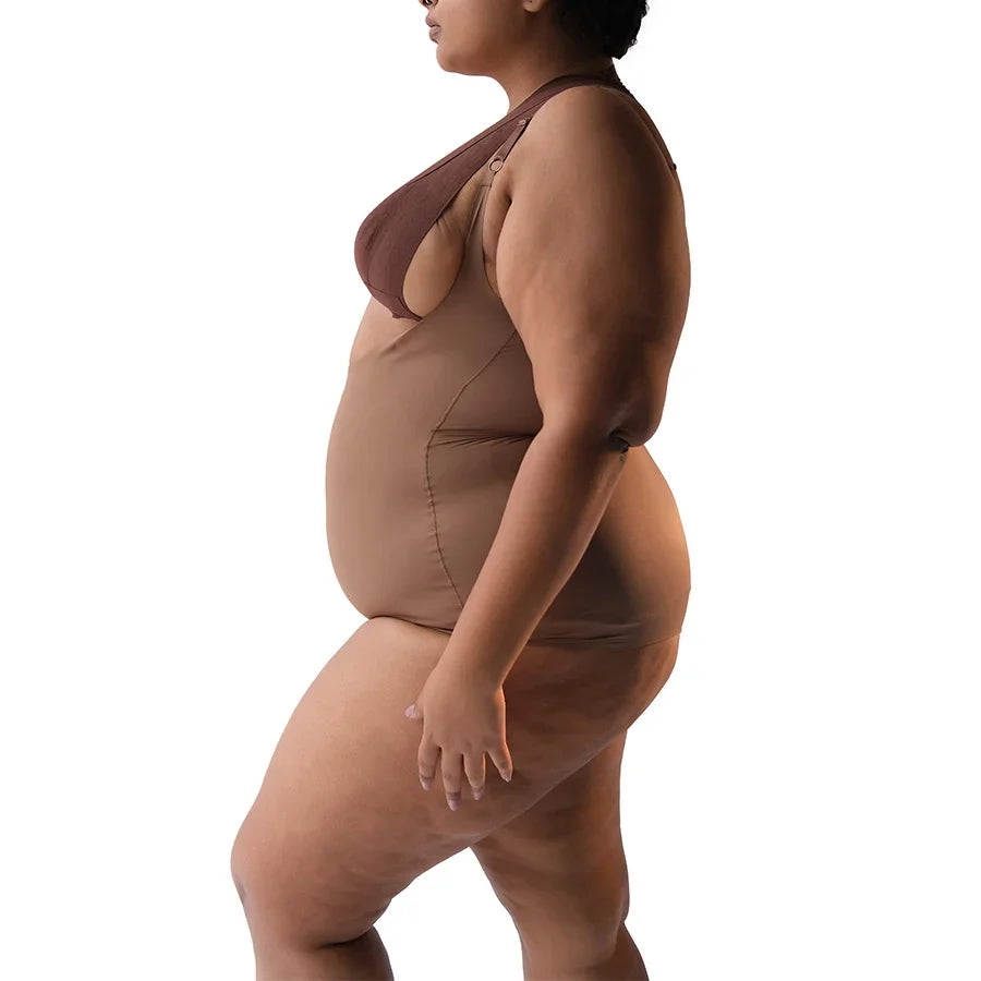 Curvy model showcasing a stylish brown bodysuit in profile.